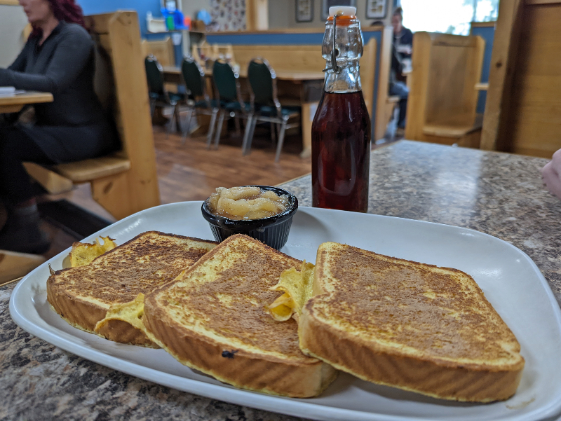 French Toast plated with a bottle of maple syrup standing on the table in Kosy Korner