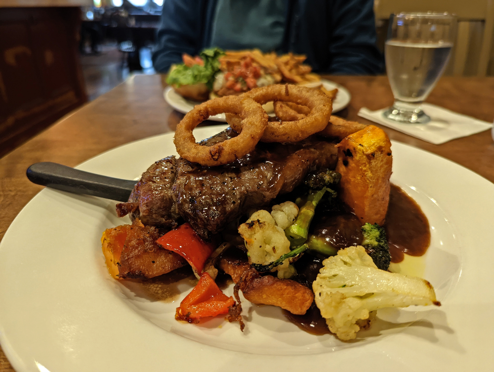 Steak topped with two onion rings and surrounded with vegetables at Mckeck’s Tap & Grill