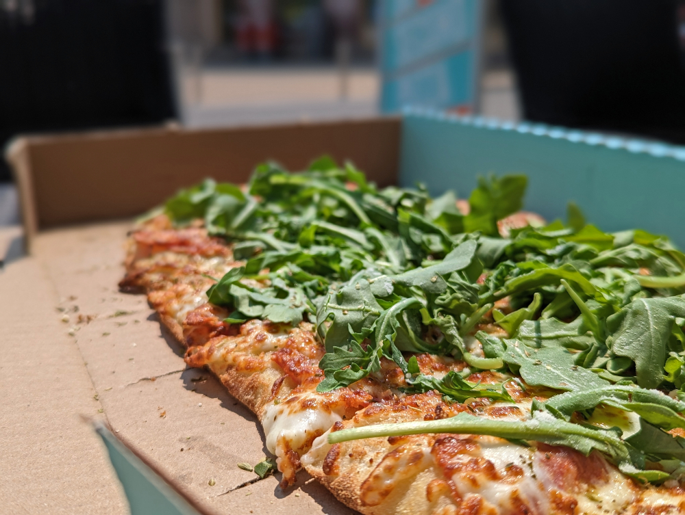 Pizza topped with arugula and cheese in a box fromP_ZZA